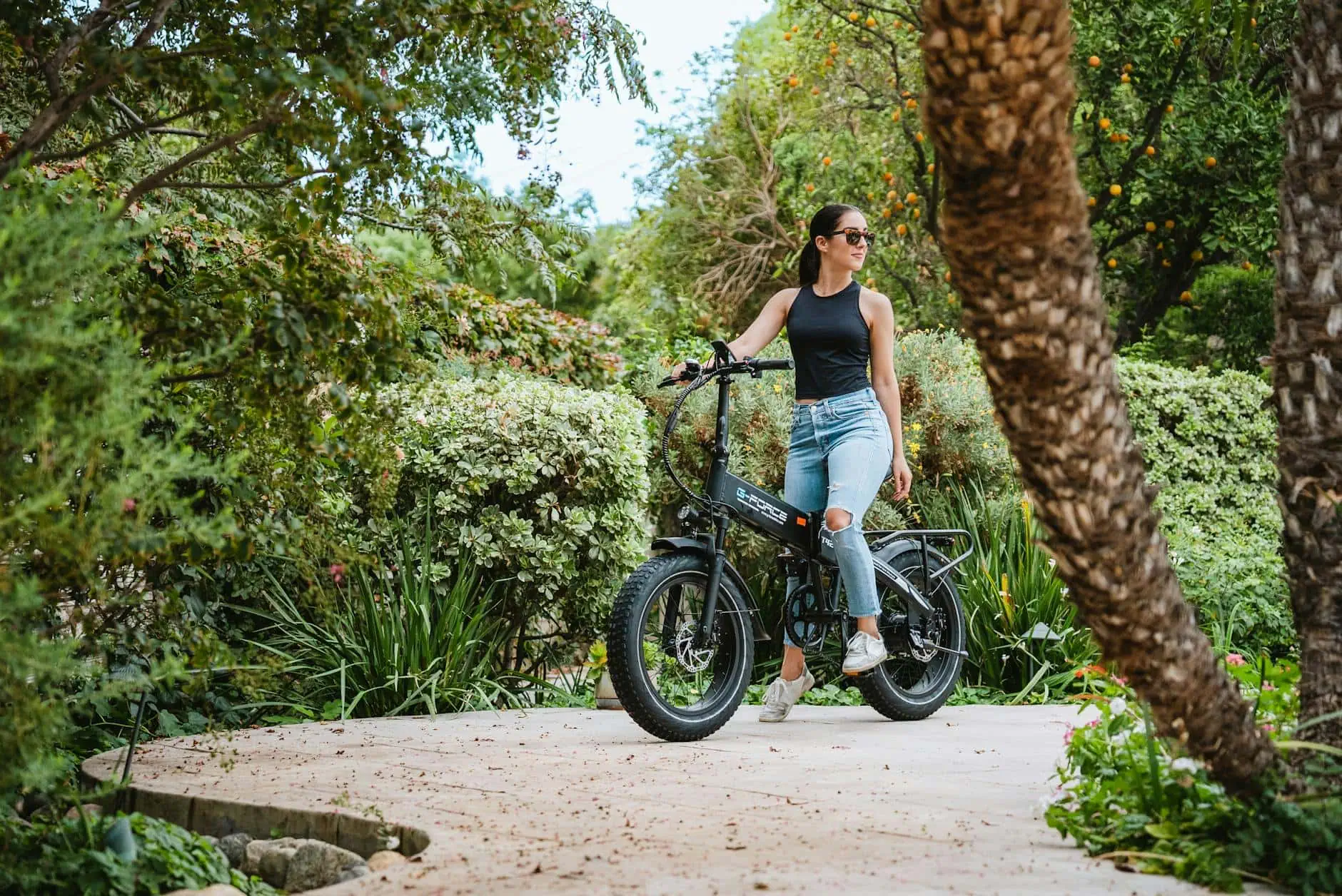 E-bike for Women. - Smittys E-bikes Woman riding electric bike through lush botanical garden, eco-friendly transportation, outdoor adventure.